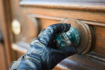 Closeup of hand of man touching a door handle with glove to protect against the coronavirus in the street