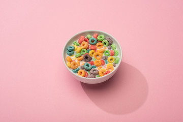 bright colorful breakfast cereal with milk in bowl on pink background