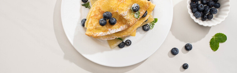 top view of tasty crepes with blueberries and mint on plate on grey background, panoramic shot