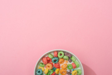Fototapeta na wymiar top view of bright colorful breakfast cereal with milk in bowl on pink background