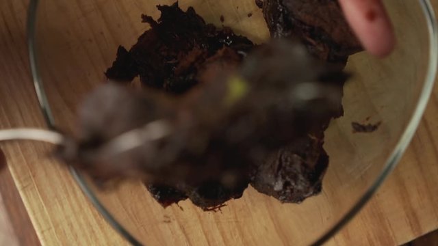 Close up of a hand scooping out the flesh of a ripe fibrous black sapote