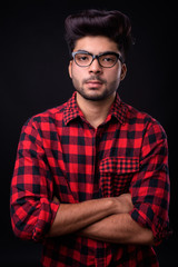 Young handsome Indian man against black background