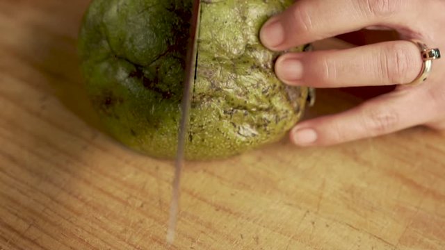 Chef cutting open a soft, ripe, black zapote in slow motion with a chef's knife