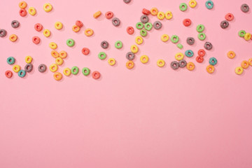 Naklejka na ściany i meble top view of bright multicolored breakfast cereal scattered on pink background