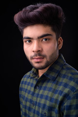 Young handsome Indian man against black background