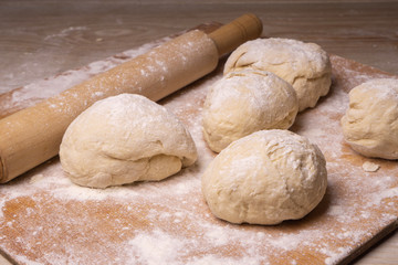 Balls of dough. Plywood cutting board, wooden flour sieve and wooden rolling pin - tools for making dough.