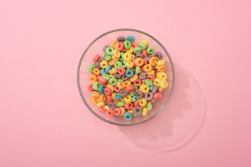 top view of bright colorful breakfast cereal in bowl on pink background