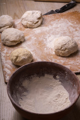 Balls of dough. Plywood cutting board, wooden flour sieve and wooden rolling pin - tools for making dough.