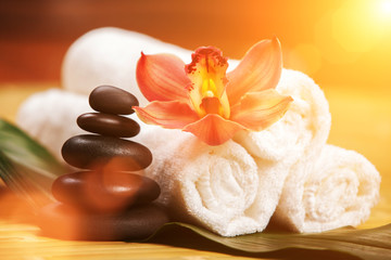 Spa background. White towels on exotic plant, beautiful orchid flower and balancing stones for...