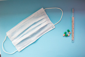 Virus prevention and treatment: wearing masks, hand disinfection, taking antiviral drugs and vitamins. First aid kit with medicines on a blue background.