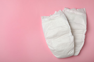 Baby diapers on pink background, top view. Space for text