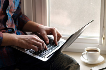Man using laptop in home office. Male hands typing on keyboard