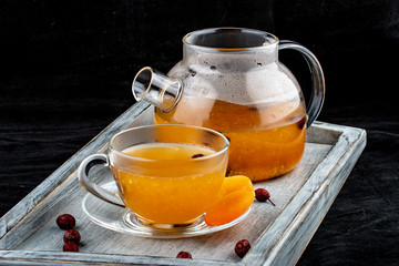 Hot tea with orange and lemon in a glass teapot. On dark background