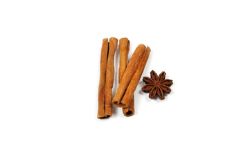 three cinnamon sticks, one on top of two, on the right side of the star anise on a white background close-up view from above