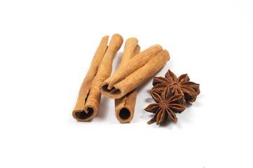 three cinnamon sticks, one on top of two, on the right side two star anise on a white background top view side view close-up