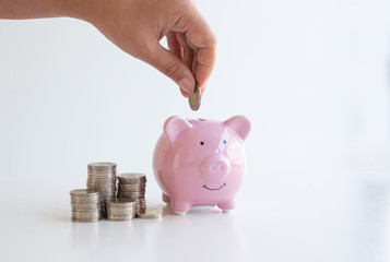 The businessman's hand holds the money in the piggy bank for saving money for future use, saving money for finance accounting concept.