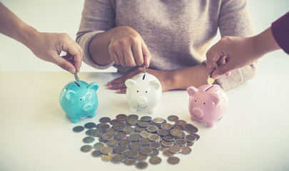 Both male and female businessmen are helping to bring the dollar into the piggy bank to save and...