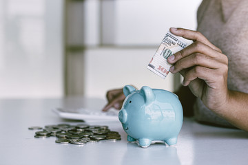 The businessman's hand holds the money in the piggy bank for saving money for future use, saving...