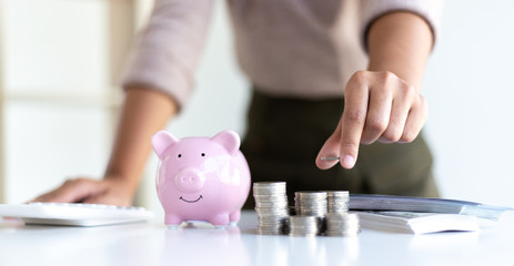 The businessman's hand holds the money in the piggy bank for saving money for future use, saving money for finance accounting concept.