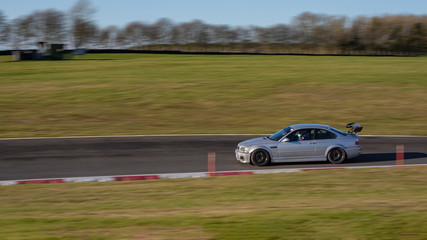 A panning shot of  a silver car cornering.