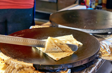 Making crepes pancakes at a market. A crepes is folded up.