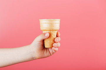 Waffle ice Cream Cup in a child's hand on a pink background.