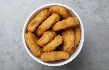 Bucket with tasty chicken nuggets on grey table, top view