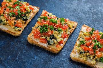 healthy homemade sandwiches with diced tomatoes cream cheese spinach scrambled egg sesame seeds parsley on dark blue background 