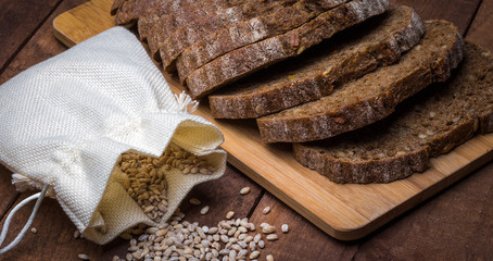 bag of grain with black bread on a wooden surface