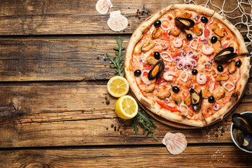 Fototapeta na wymiar Delicious seafood pizza on wooden table, flat lay. Space for text