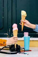 Detail of two hands holding ice creams with a cone