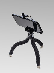 Mini-tripod with smartphone photography, on a light gray background