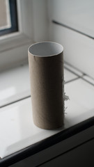 Cardboard tube of a roll of toilet paper stands alone, empty on a bathroom tiled shelf. Panic buying has caused a shortage  around the world. During this coronavirus pandemic we are seeing shops empty