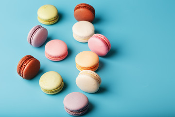 Multicolored French macaroni macaroni cookies on a blue background. Free space, top View.