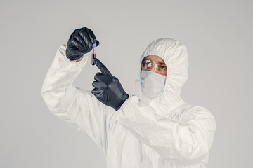 A test tube in a man's hand close-up , a man in a medical mask holding a bottle of red liquid....