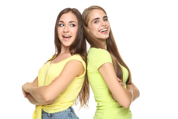 Young happy girlfriends standing by the back to each other on white background