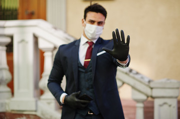 Concept of coronavirus quarantine. Business man wear on suit with medical face mask and mobile phone at hand show stop sign. MERS-Cov, Novel coronavirus 2019-nCoV