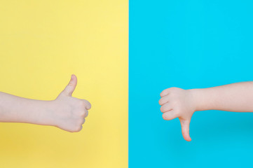 Children's hands show thumb down on a blue background and thumb up on a yellow background. Place for text for designers.