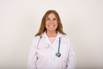 Portrait of charming doctor female wearing medical uniform looking up with enigmatic smile.