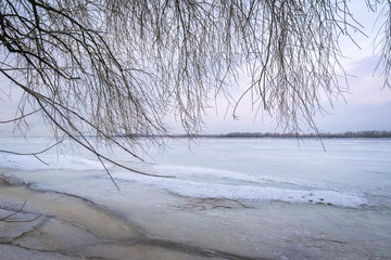 Winter landscape at dawn, riverbank of a frozen ice.