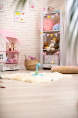 Handmade plush giraffe made of fabric sits on fluffy carpet in children 's room.