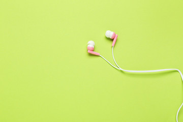 Fototapeta na wymiar Pink earphones on green background