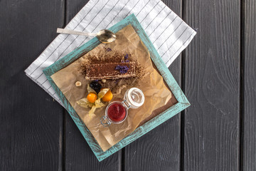 Piece of chocolate cake with strawberry jam on black wooden table