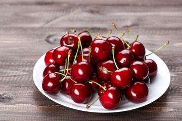 Sweet cherries in plate on wooden table