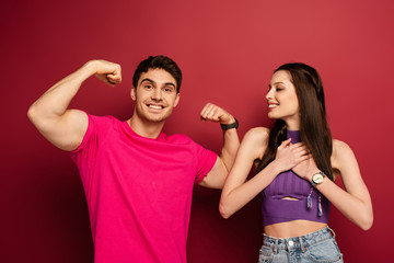 strong musclar man with cheerful girlfriend on red