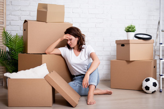 financial or relationship problems - young stressful woman sitting with cardboard boxes