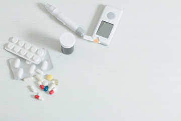 glucometer and pills on  white wooden table