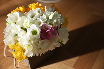 Beautiful bouquet with spring freesia flowers on sunlit wooden table
