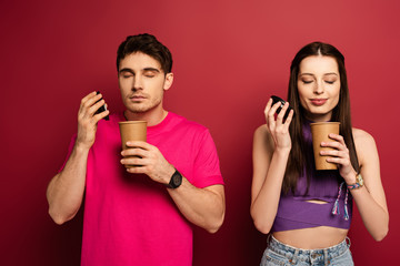 beautiful couple smelling coffee to go on red