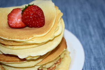 stack of pancakes with maple syrup and strawberry